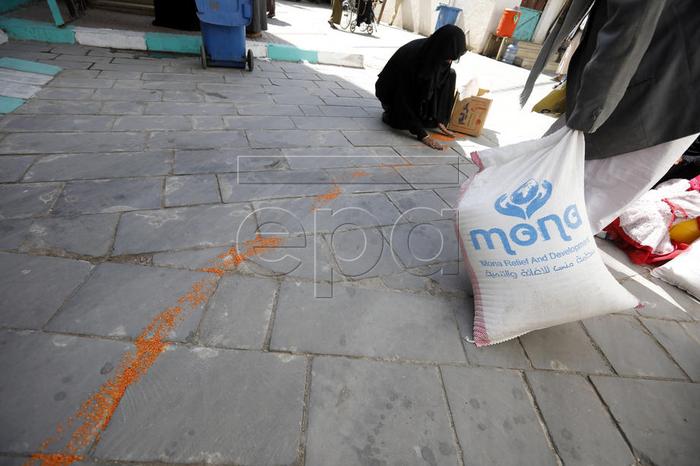 epa08002319 A conflict affected Yemeni woman collects spilled grain from the floor, after getting food rations provided by Mona Relief Yemen in Sanaa, Yemen, 16 November 2019. According to reports, the ongoing conflict in Yemen since 2015 has created the worst humanitarian crisis in the world, with 10 million people living with extreme hunger and two million children under five already acutely malnourished, as the Arab country enters its fifth year of armed conflict between the Saudi-backed Yemeni government forces and the Houthi rebels.  EPA-EFE/YAHYA ARHAB